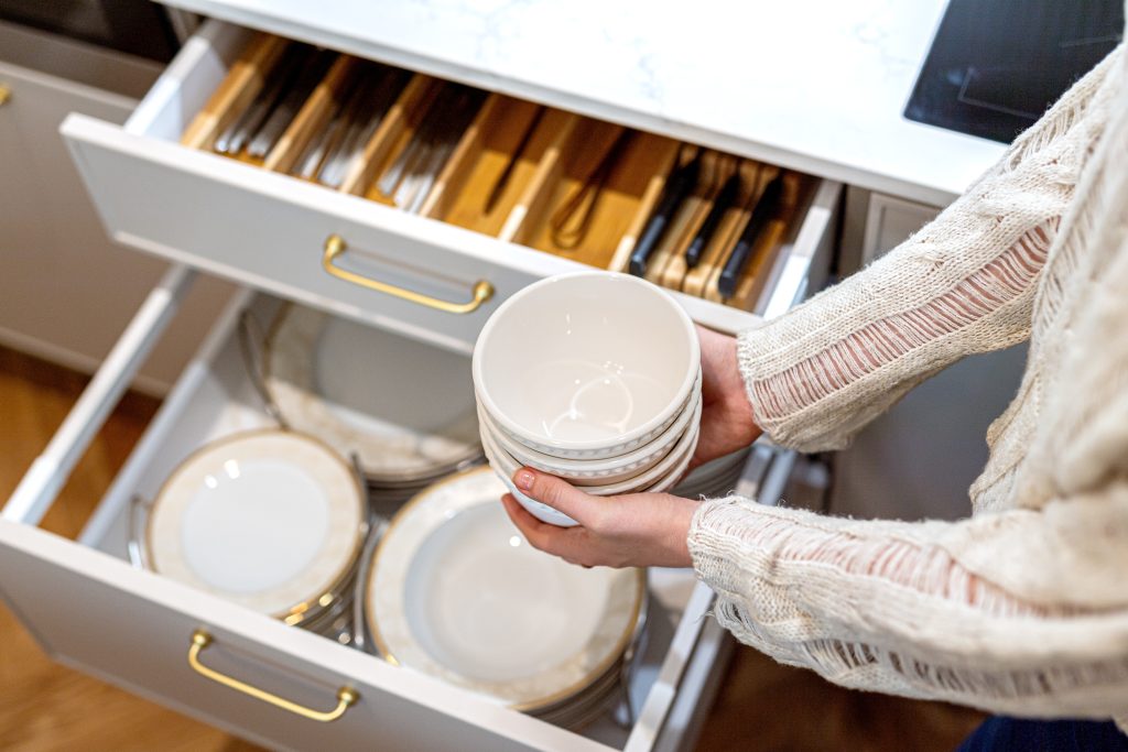 Declutter your kitchen with woman arm putting plate in drawer