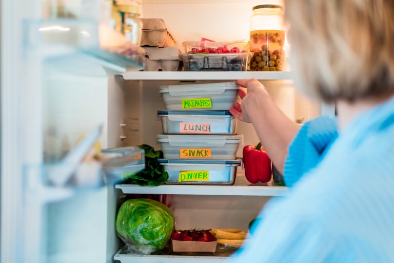 Fully stocked fridge with meal prepped dishes that have been batched cooked
